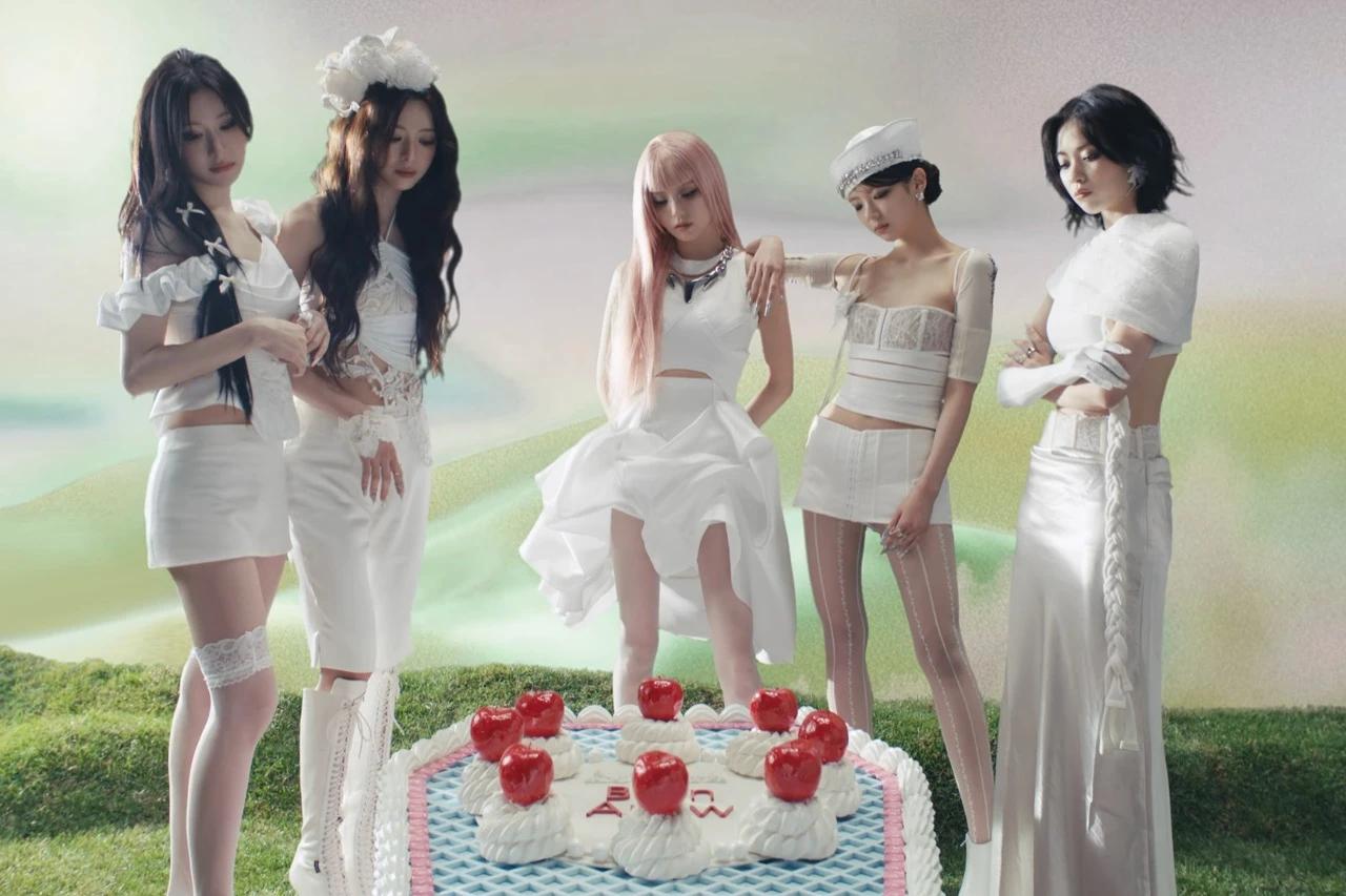 All five ITZY members pose around a decorated cake in white styling for the Motto teaser scheduler.
