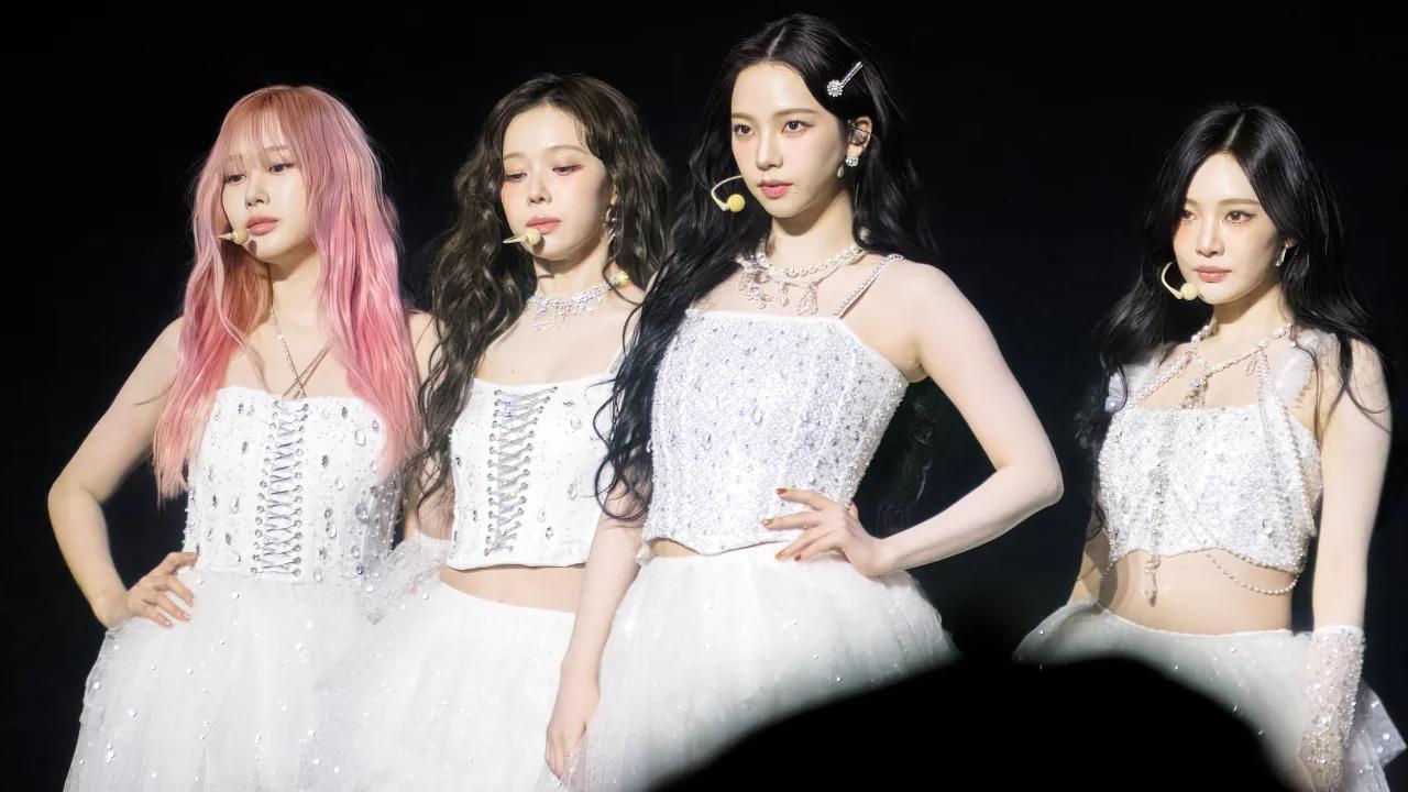 aespa performing live on stage in white sparkly outfits during their SYNK aeXIS LINE world tour