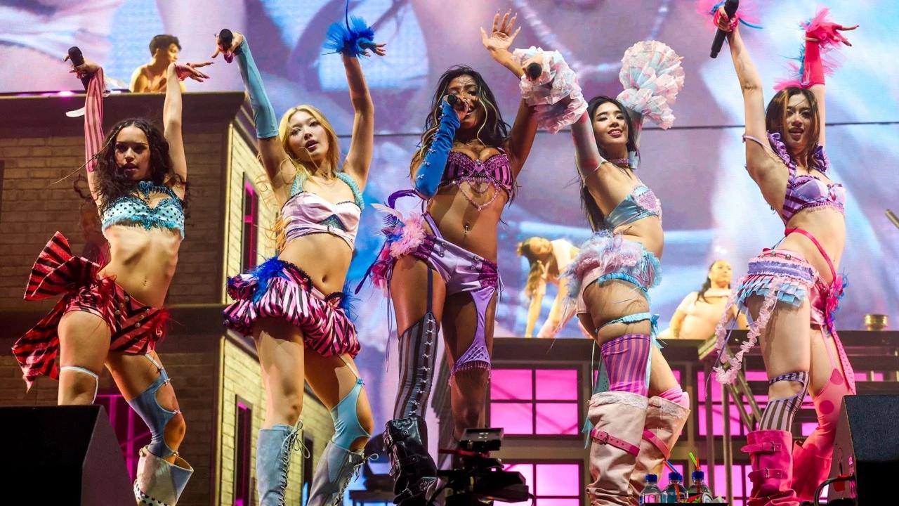 Five KATSEYE members perform onstage during Coachella 2026 under pink lighting