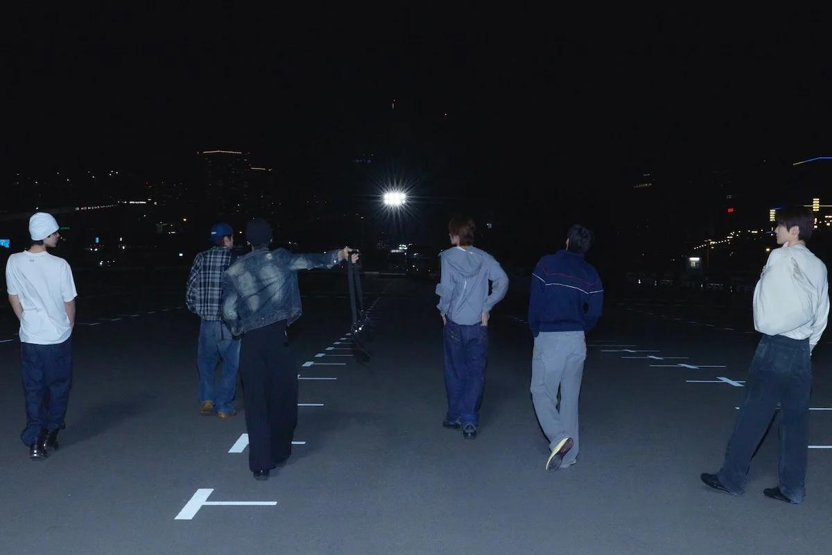 RIIZE members walking across an open lot at night in teaser imagery for the II comeback